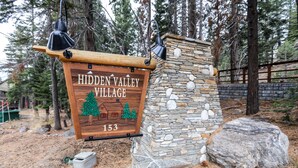 Un panneau en bois, posé sur un socle en pierre, portant l’inscription « Hidden Valley Village 153 ».