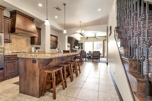 Una cocina amplia con una isla central, taburetes de madera y luces colgantes.