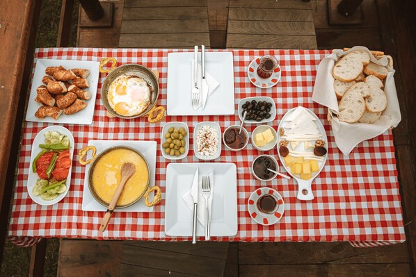 A picnic setup with a checkered tablecloth, various food items, and utensils. - Mini Lui Bungalov Butik Otel (Arhavi)