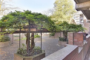 Stroll through a serene courtyard surrounded by lush foliage and brick walls.