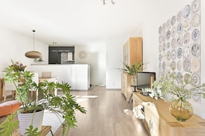Enjoy a comfortable seating area with a large potted plant and a console table holding a television and vase.