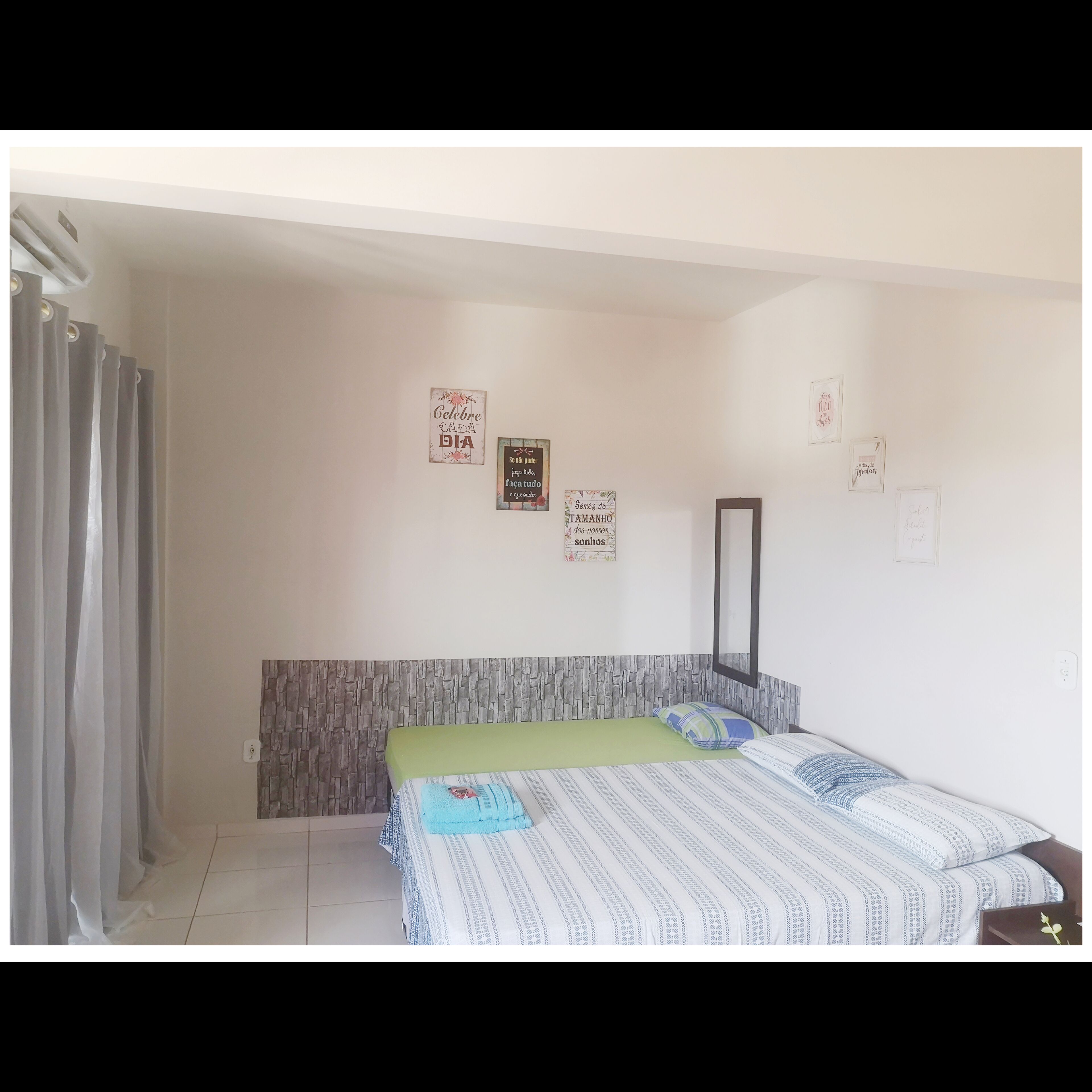 Une chambre à coucher avec un lit, une tête de lit et un mur orné de plusieurs tableaux encadrés.