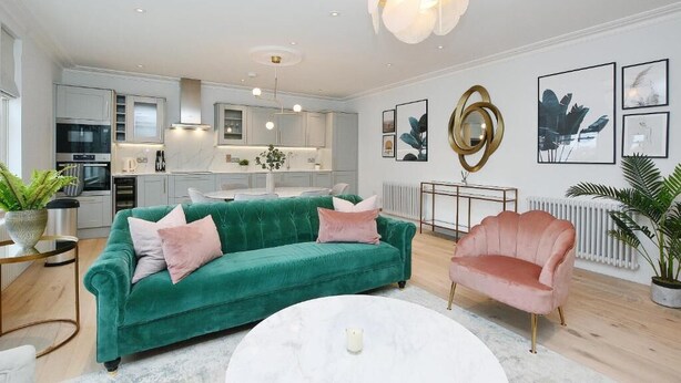 A modern living room with a green sofa, a pink armchair, and a white coffee table. - 3 bedroom apartment in the heart of Kensington (London)