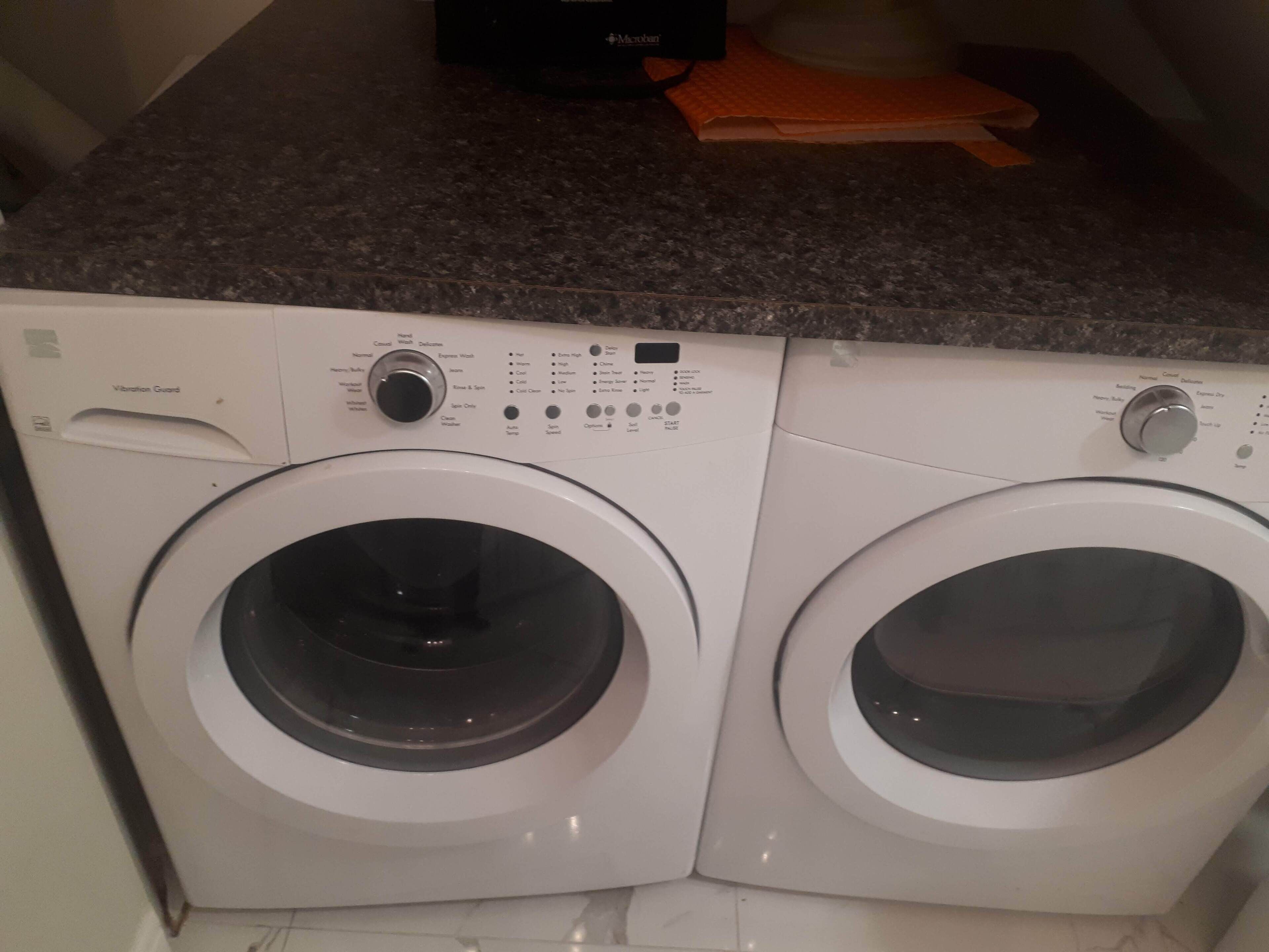 Vista frontal de una lavadora de carga frontal con panel de control y una secadora apilada encima.