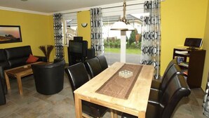 Un salon avec une table à manger en bois, un canapé en cuir noir et un téléviseur.