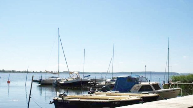 Un port de plaisance avec plusieurs bateaux amarrés, une jetée en bois et une eau calme.
