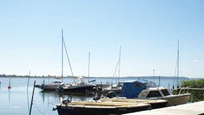 A marina with several boats docked, a wooden pier, and calm water. - Modern vacation home with a large garden (2 DHH) (Glowe)