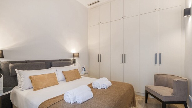Ein modernes Hotelzimmer mit einem großen Bett, einer Sitzecke und einem Kleiderschrank.