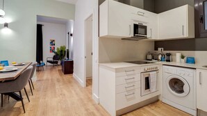 A compact kitchen with a microwave, toaster, and washing machine. - Sweett | Sepulveda Principal A (Barcelona)