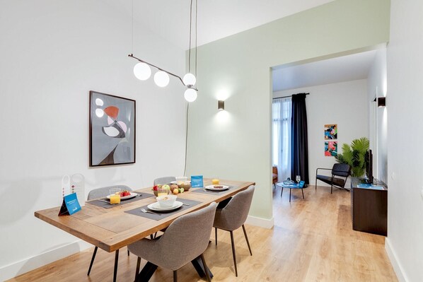 Un comedor moderno con una mesa de madera, sillas tapizadas grises y una lámpara contemporánea.