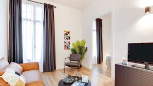 A modern living room with a sofa, a coffee table, a chair, a TV, and a plant. - Sweett | Sepulveda Principal A (Barcelona)