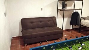 A room with a sofa, a foosball table, and a metal shelf with a coat hanging on it. - El Teotihuacano is 1.5 km away. From the archaeological zone (San Juan Teotihuacan)