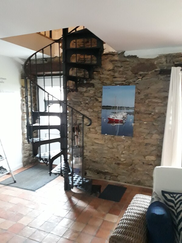 A spiral staircase with a stone wall backdrop, a framed picture of a boat, and a checkered floor. - SUPERBLY RENOVATED AND DECORATED OLD HOUSE - SPACIOUS GARDEN (PENVINS)