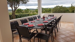 A dining table set for six with black chairs, red napkins, and wine glasses, overlooking a scenic landscape.