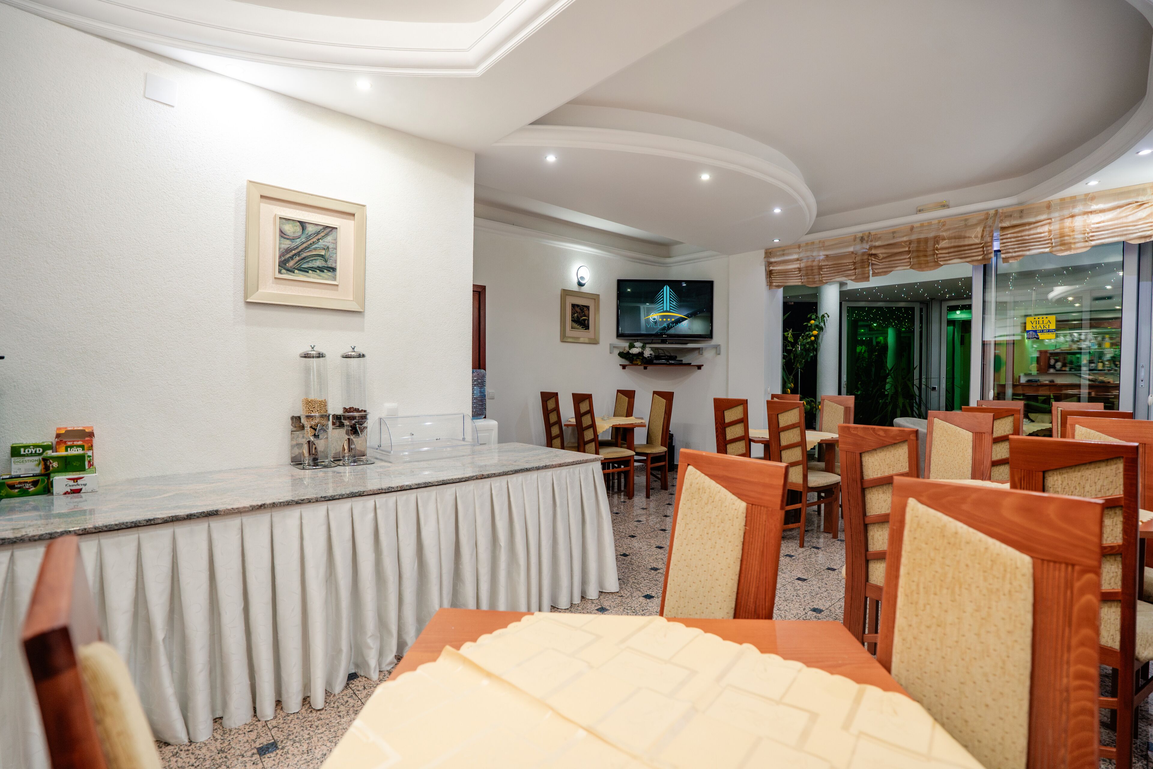 Un espace de restauration dans un hôtel, comprenant un bar, des chaises et un téléviseur.