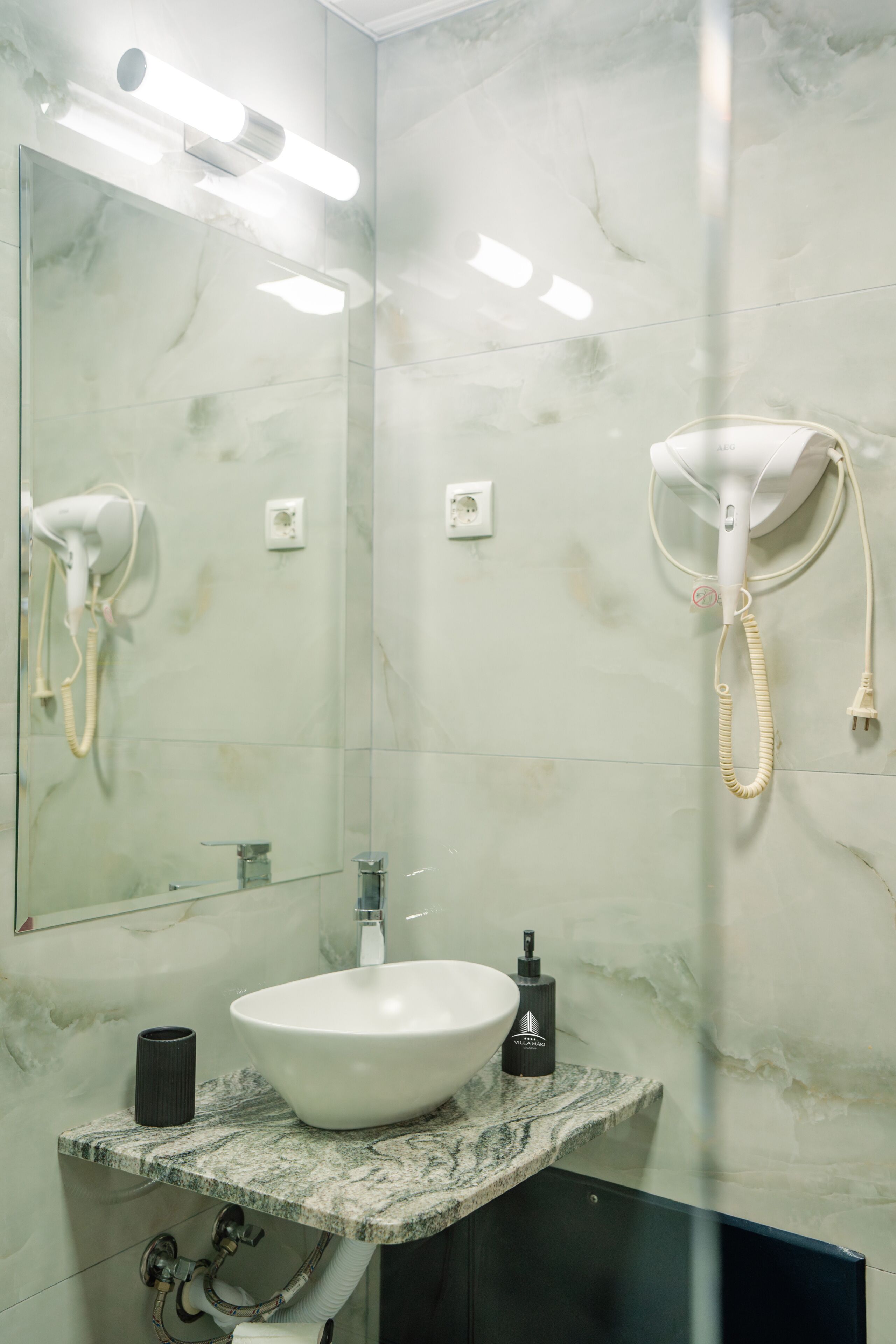 A bathroom with a marble sink, a mirror, a hairdryer, and a towel rack.