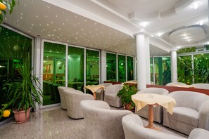 A modern indoor space with seating, tables, and large windows. - Villa Maki (Ohrid)