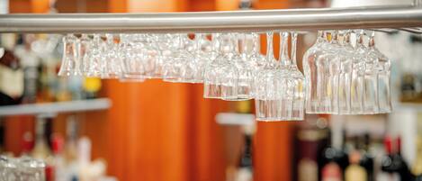 A bar area with a row of empty glasses hanging from a metal bar.