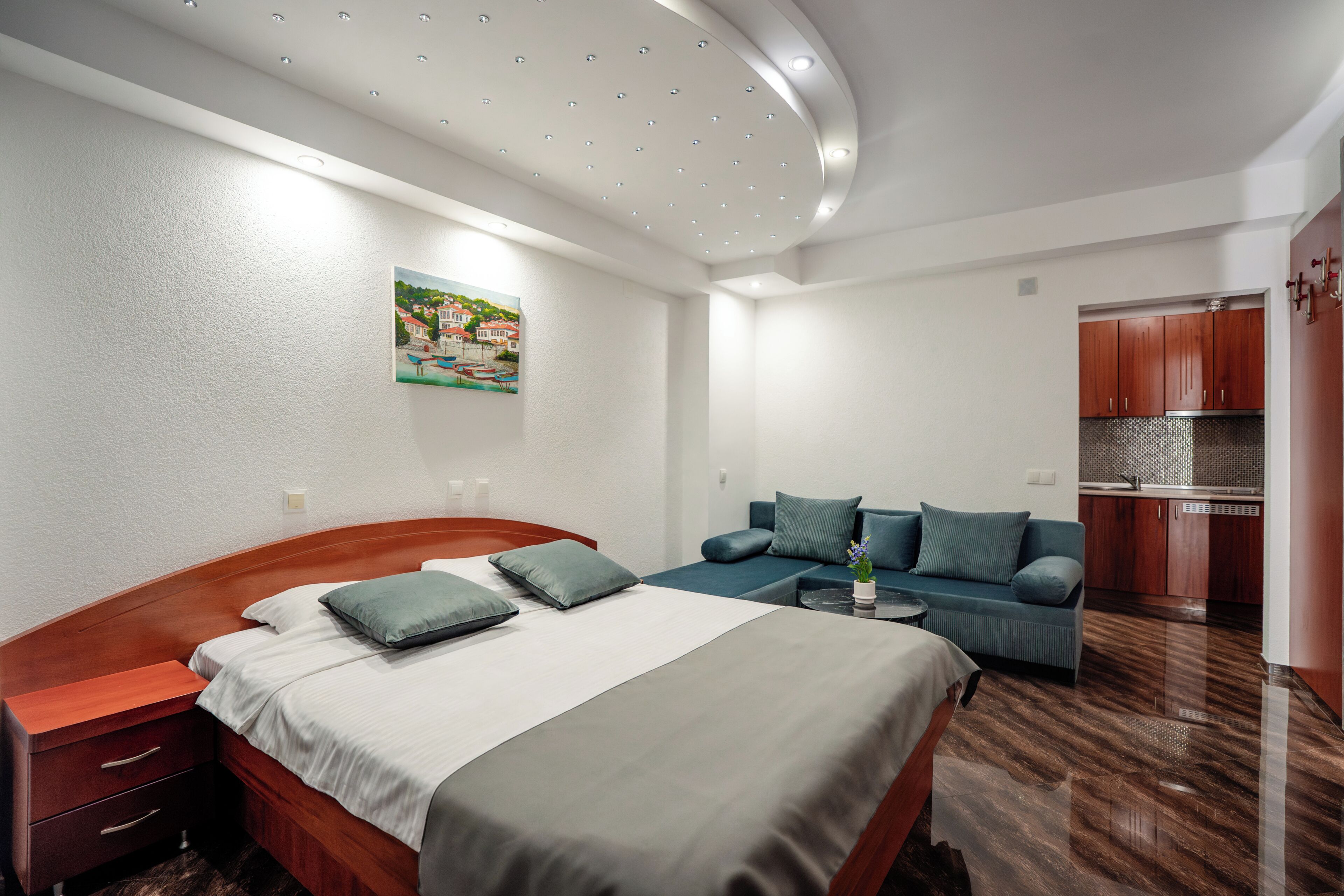 Une chambre d’hôtel moderne équipée d’un lit, d’un canapé, d’une petite table et d’une kitchenette.