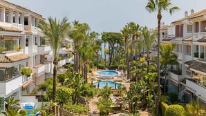 Een resort met meerdere zwembaden, palmbomen en witte gebouwen.