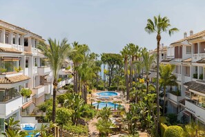 Un complexe hôtelier doté de plusieurs piscines, de palmiers et de bâtiments blancs.