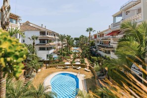 A resort with a swimming pool, palm trees, and modern buildings.
