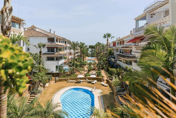 Ein Resort mit Swimmingpool, Palmen und modernen Gebäuden.