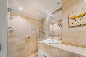 Ein modernes Badezimmer mit einer Duschkabine aus Glas, einem weißen Waschbecken und einem dekorativen Schmetterlingsbild an der Wand.