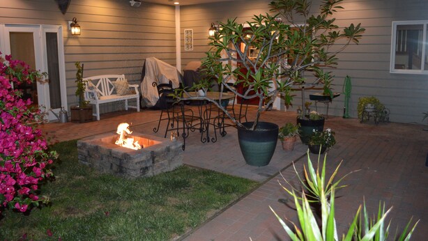 Un patio con pozo de fuego, asientos y plantas en macetas.
