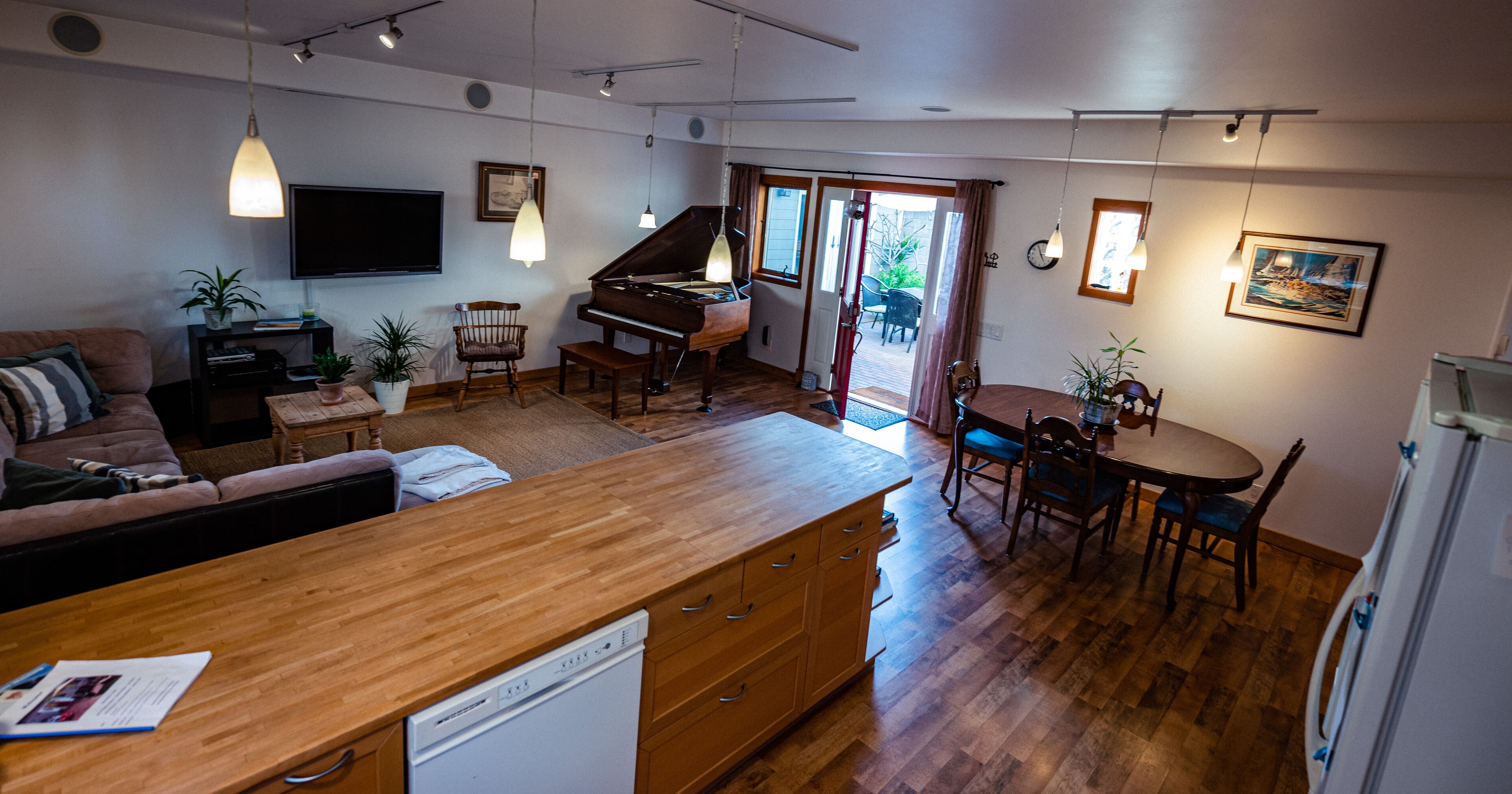 A modern living room with a piano, dining area, and kitchen.