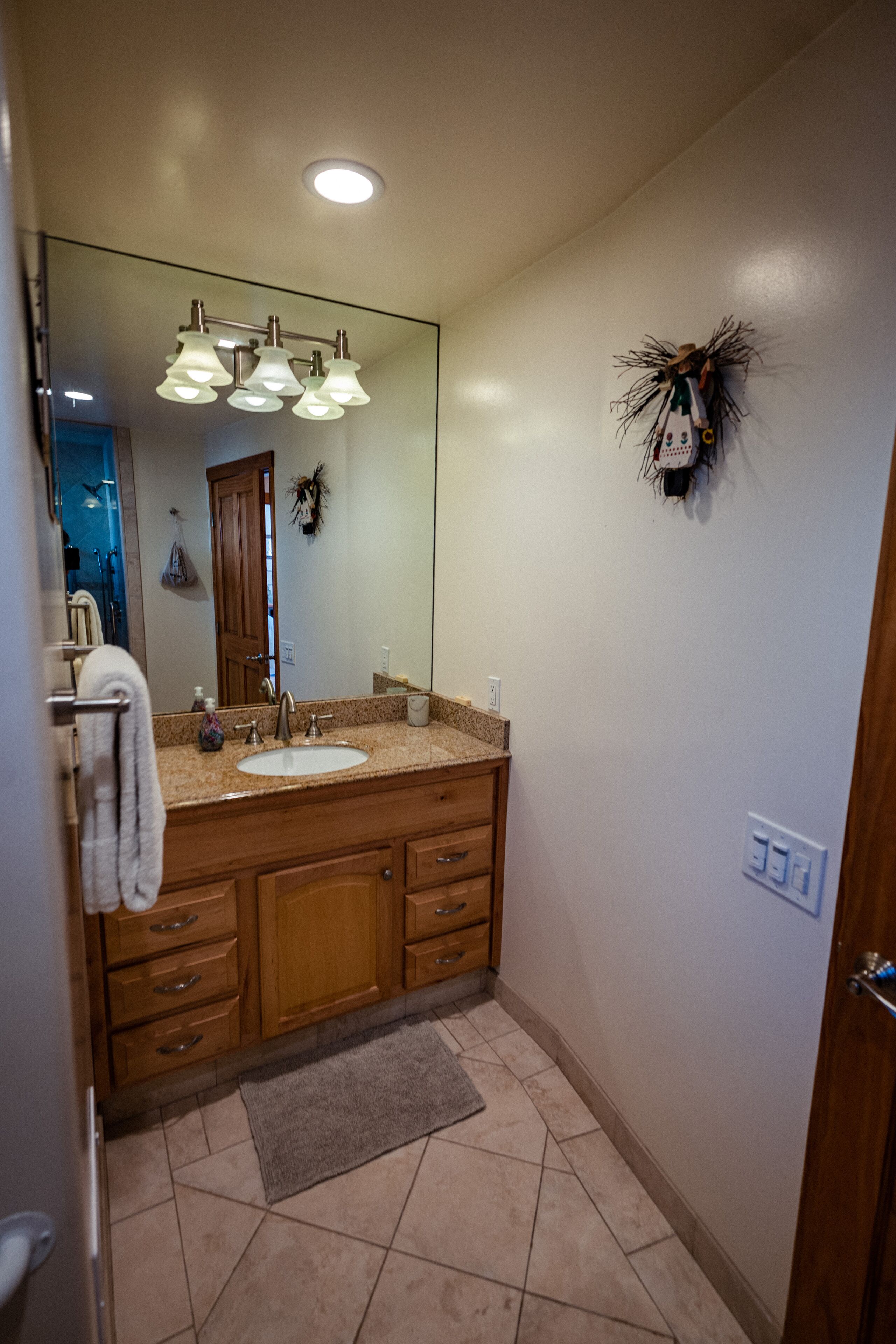 A bathroom with a large mirror, a sink, a vanity with drawers, and a towel rack.