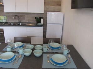 Una cocina moderna con armarios blancos, un lavamanos de acero inoxidable y un refrigerador empotrado.