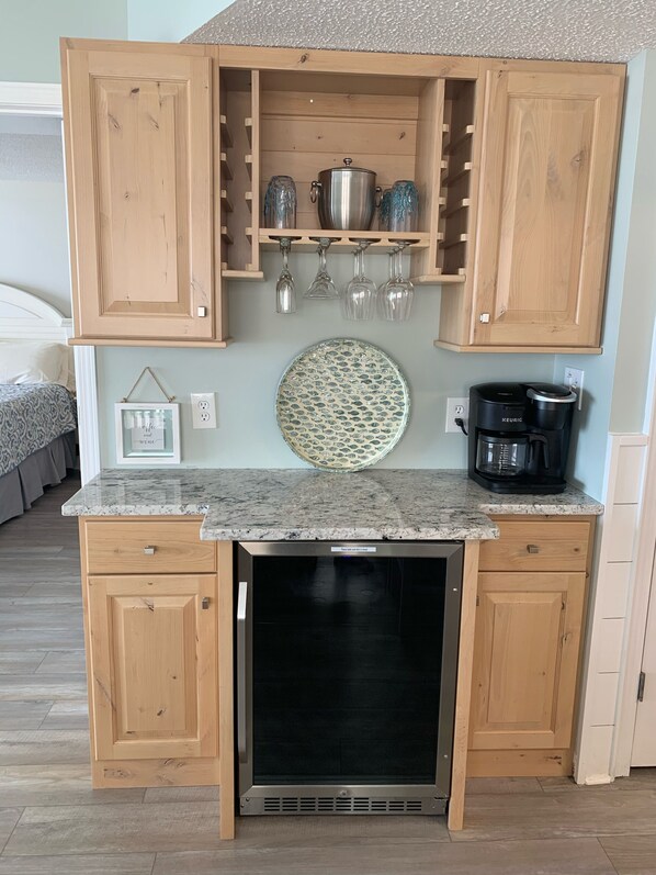 A compact kitchen with wooden cabinets, a built-in dishwasher, a coffee maker, and a decorative plate on the counter. - Enjoy our beachfront property! (North Myrtle Beach)