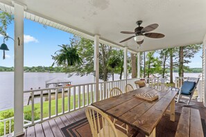 Una terraza de madera con una mesa y sillas, con vista a un lago.