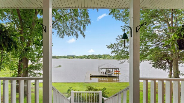 Eine überdachte Terrasse mit Seeblick, ein Pavillon und eine Rasenfläche.