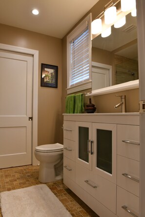 Bathroom features a toilet, sink, and cabinet with drawers, along with a towel rack and framed picture.