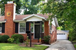 Stunning home with a brick facade, front porch, and attached garage, set amidst beautifully maintained lawns and lush greenery.