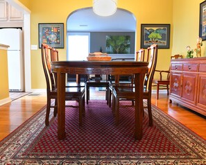 Enjoy meals in this cozy dining area with a wooden table and chairs, surrounded by artwork and a large window.