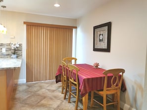 A dining area with a table set for four, wooden chairs, a tiled floor, a window with blinds, and a framed picture on the wall. - Entire Cozy Unit (3BD/1BR) N San Jose w/ free parking near San Jose Airport (San Jose)