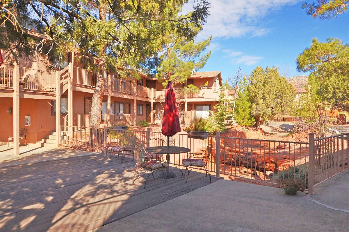 A multi-story building with balconies, outdoor seating, and a fenced patio area.