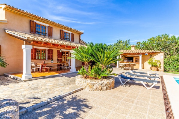 A villa with a patio, outdoor seating, and a pool area.