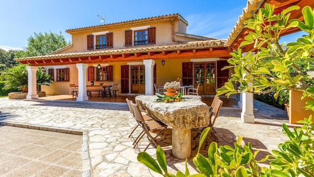 A two-story building with a patio area featuring stone flooring and a table with chairs. - REI PETIT.  Splendidly maintained garden for a perfect experience (Pollensa)