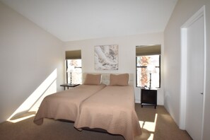 A bedroom with a large bed, two bedside tables, a nightstand, and a window with curtains.