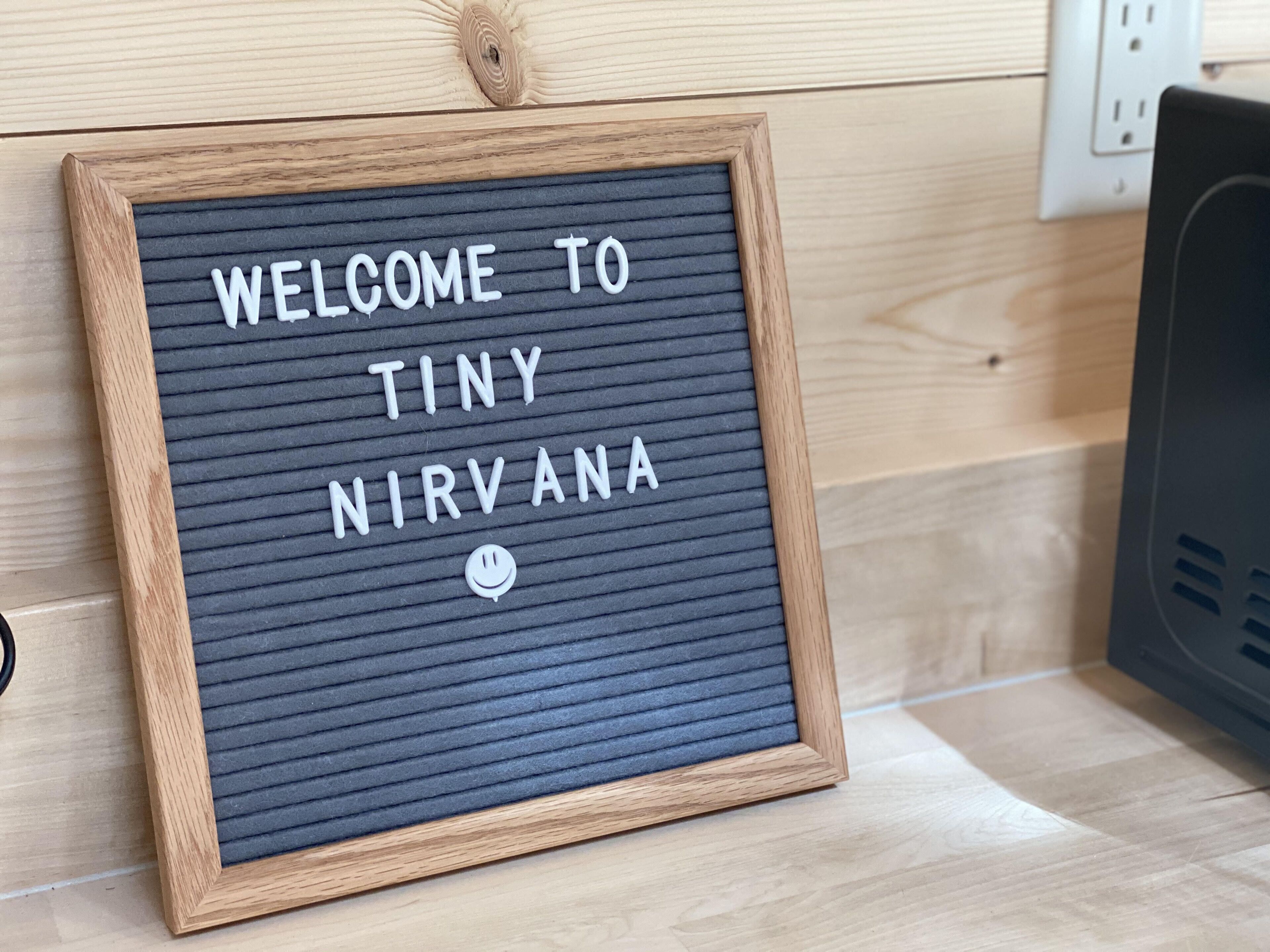 A framed sign with the text "WELCOME TO TINY NIRVANA" on a textured background.