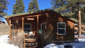 A small lodge named Cedar Cabin with a porch, a bench, and a sign indicating a catch and release fishing area.