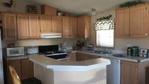A kitchen with wooden cabinets, a central island, a microwave, a stove, and a sink.