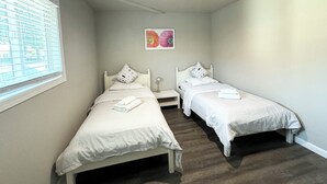 A room with two single beds, a small bedside table, a wall-mounted light, and a window with blinds. - Beautiful, Safe, Clean, Spacious 2 bd/1ba in N San Jose 951311 (San Jose)