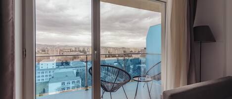 Quarto com uma grande porta de vidro deslizante que dá para uma varanda com vista para a cidade.
