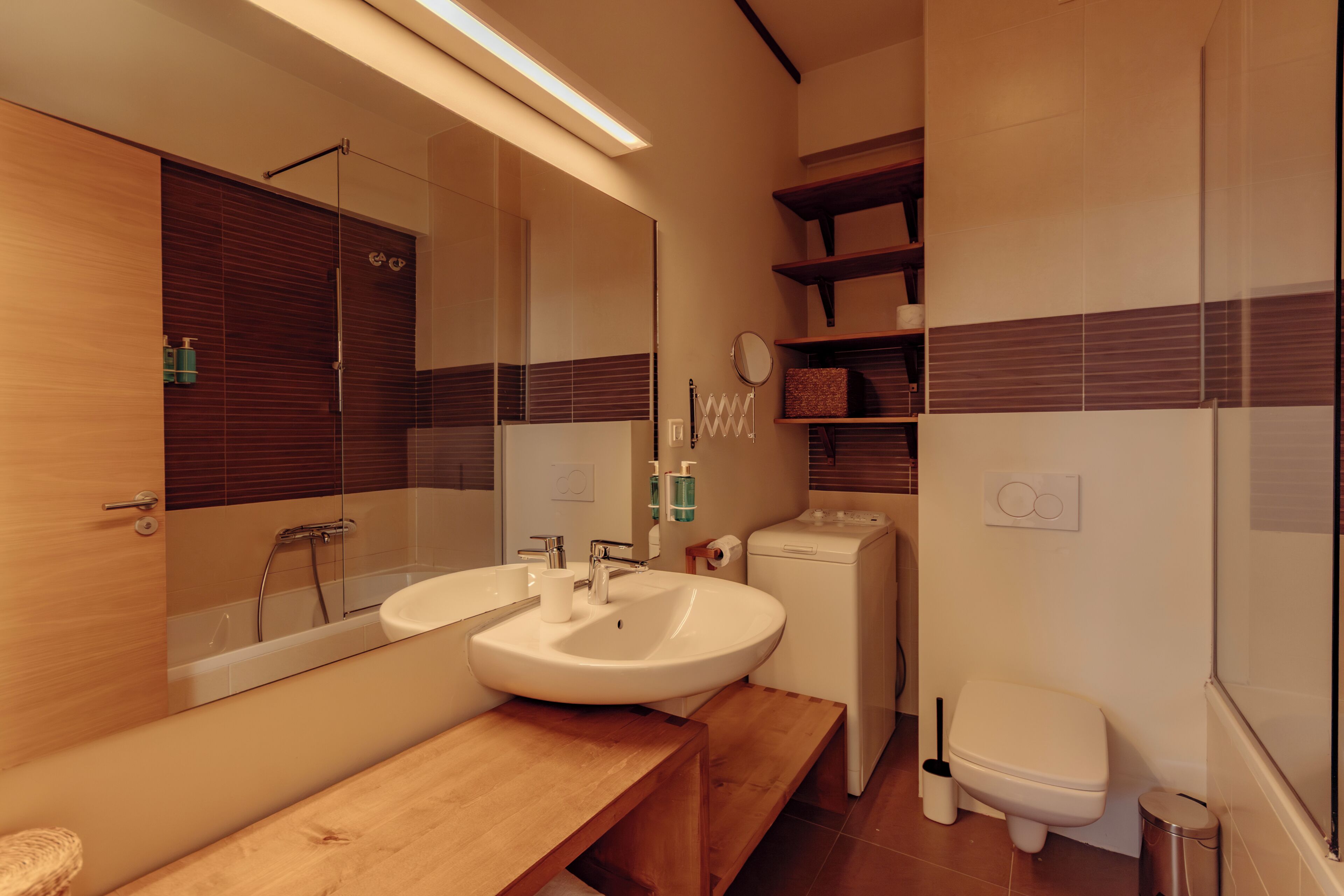 A modern bathroom with a double sink, a mirror, a toilet, and a shower.