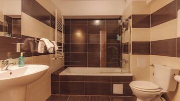 Un baño moderno con bañera, inodoro, lavamanos y cabina de ducha de vidrio.